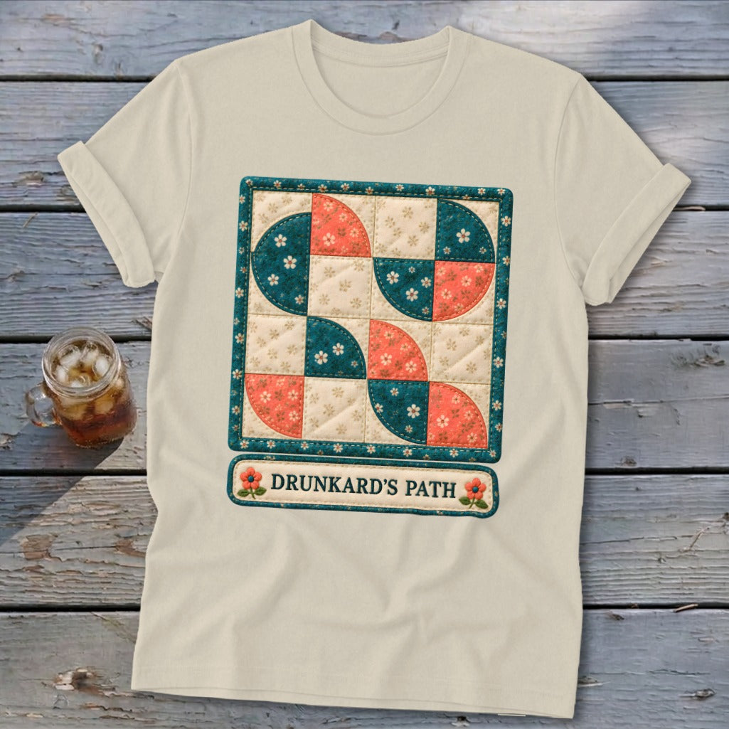 Cream t-shirt with "Drunkard's Path" quilt design featuring coral and teal quarter circles.