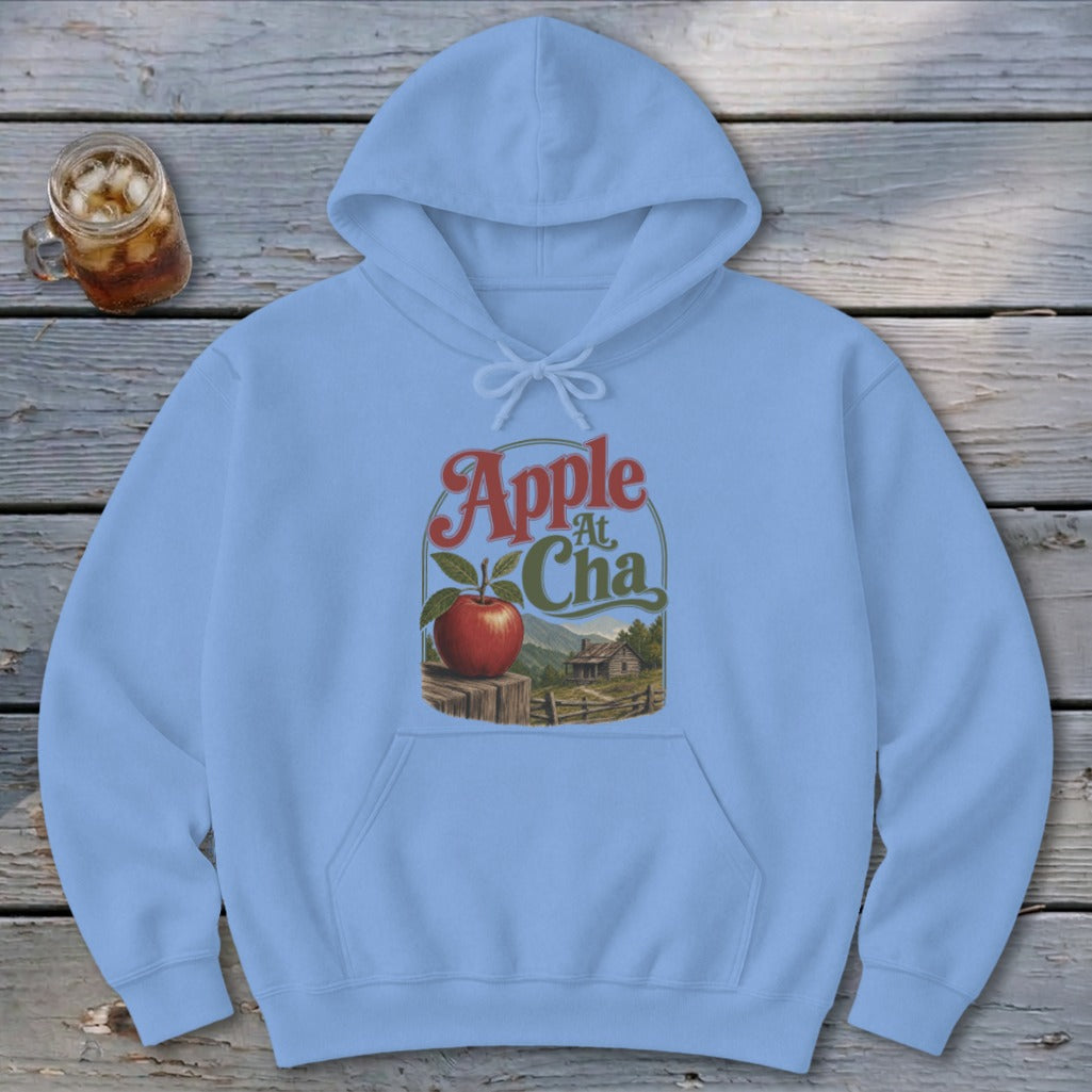A light blue hooded sweatshirt features a vintage graphic design with a red apple and cabin scenery.