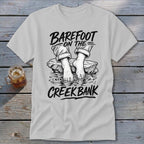 T-shirt graphic of bare feet in water with text "BAREFOOT ON THE CREEK BANK".