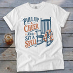 White t-shirt with "Pull up a cheer and sit a spell" and rocking chair graphic.