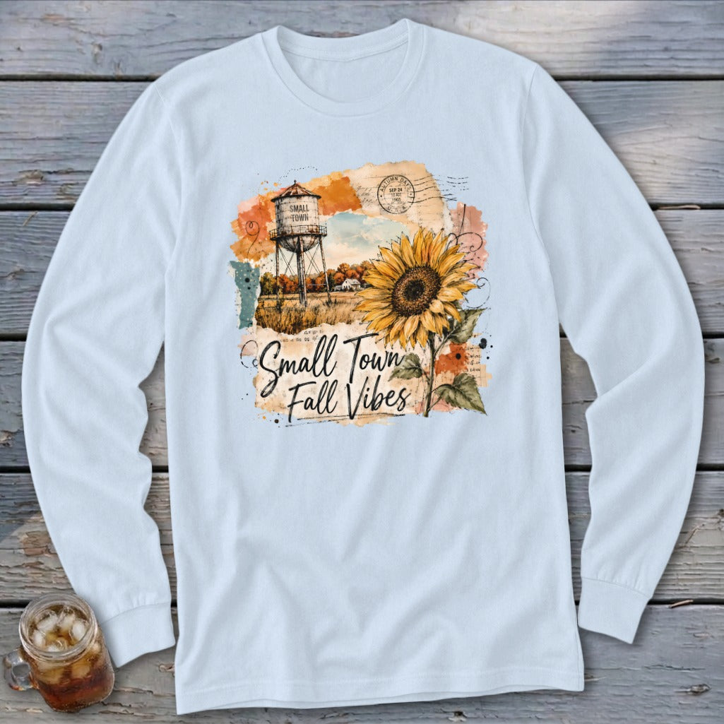Long sleeve shirt with a watercolor graphic of a water tower, sunflower, and "Small Town Fall Vibes" text.