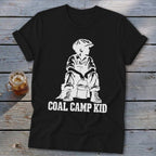 Black t-shirt with white graphic of a boy in overalls and cap holding a bucket, text reads "COAL CAMP KID".