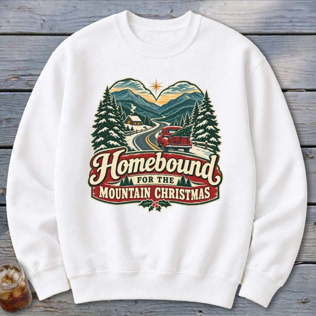 White sweatshirt with "Homebound For The Mountain Christmas" text and winter mountain scene.