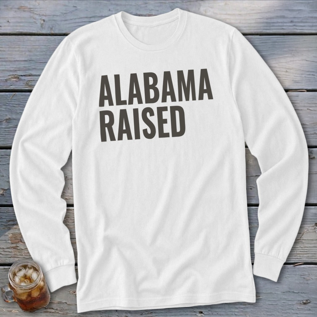 White long-sleeved shirt with "ALABAMA RAISED" printed in dark gray.