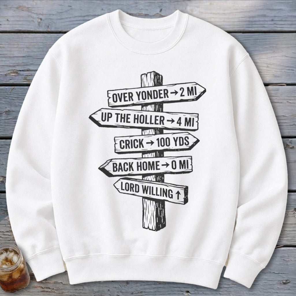 A white crewneck sweatshirt features a black graphic of a rustic wooden signpost with humorous directional text.
