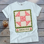 White t-shirt with a "Shoo Fly" quilt block design featuring pink flowers.