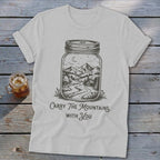 A light gray t-shirt featuring a mason jar graphic containing a mountain landscape and the text Carry The Mountains With You.