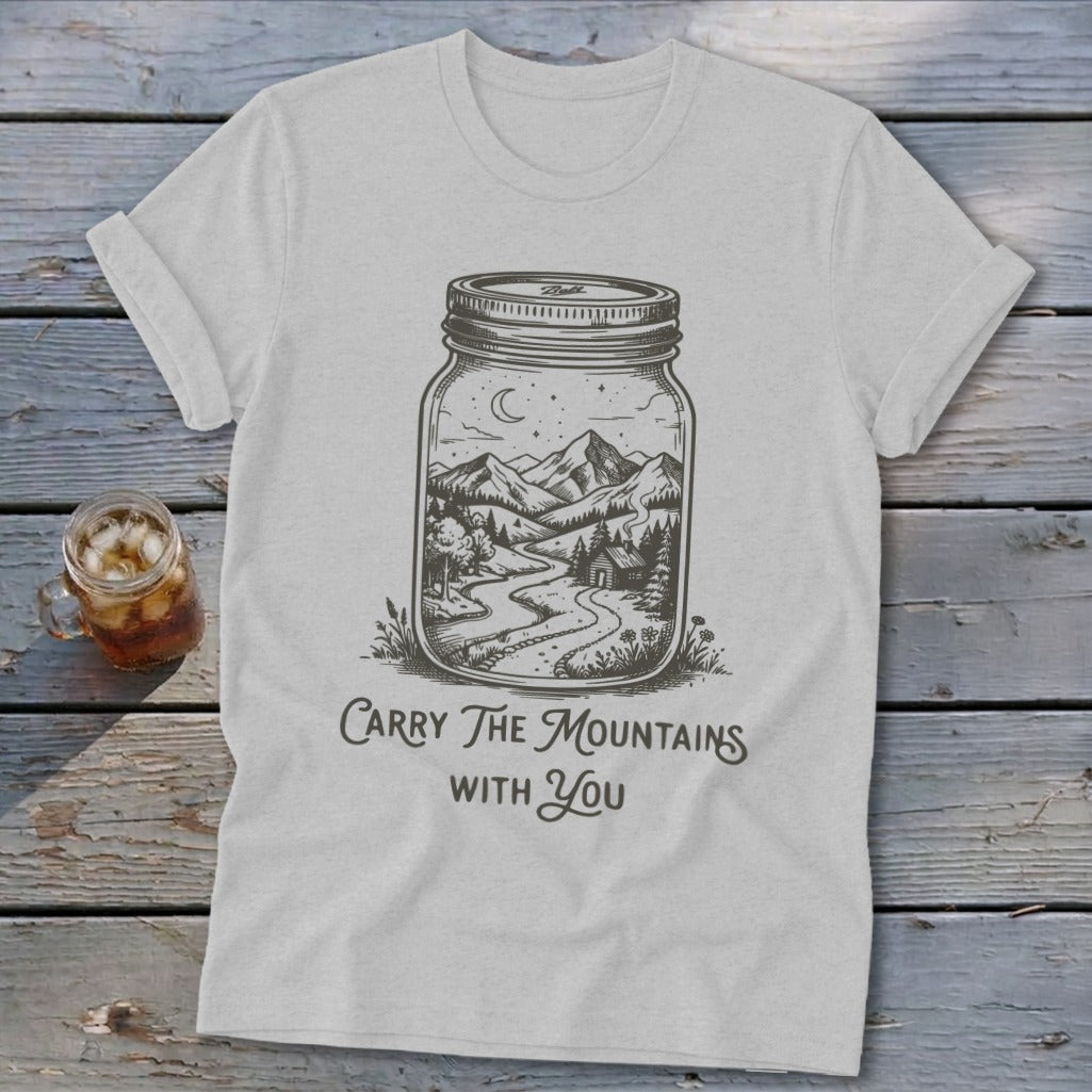 A light gray t-shirt featuring a mason jar graphic containing a mountain landscape and the text Carry The Mountains With You.