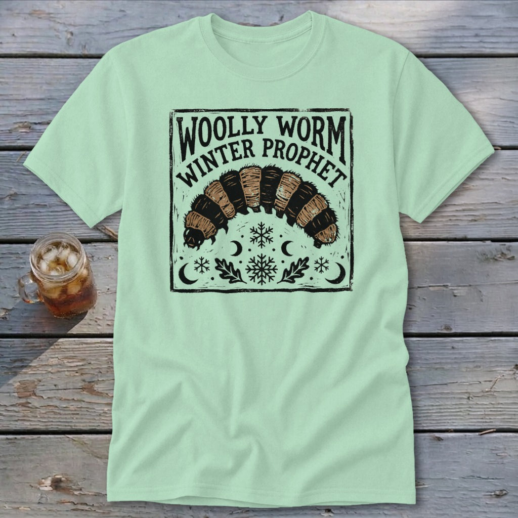 A light green t-shirt displays a black graphic featuring a woolly worm and the text Woolly Worm Winter Prophet.