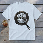 White t-shirt with graphic of a cast iron skillet and text "NO SUGAR IN THE CORNBREAD".