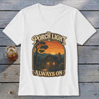 White t-shirt with graphic "The Porch Light is Always On" over a cabin at sunset.