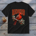 A black t-shirt features a graphic of a red cardinal on a snowy branch with red berries and the text REDBIRD.