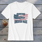 A white V-neck t-shirt featuring a graphic with an American flag and the text Ohio Raised American Made.