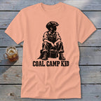 Peach t-shirt with black graphic of a boy holding a bucket and text "COAL CAMP KID".