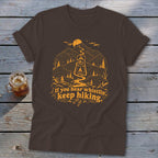 Brown t-shirt with orange graphic of lantern, mountains, and text "If you hear whistlin', keep hiking."