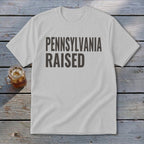 White t-shirt with "PENNSYLVANIA RAISED" in dark gray text.