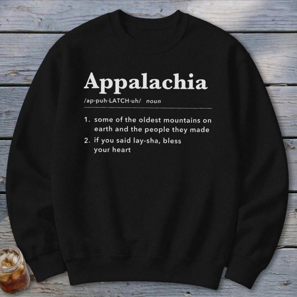 A black crewneck sweatshirt printed with white dictionary-style text defining Appalachia against a wooden background.