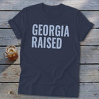 Navy t-shirt with "GEORGIA RAISED" in light blue text.