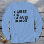 Light blue long sleeve shirt with black text that reads "RAISED ON GRAVEL ROADS".