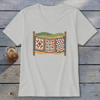 A light gray V-neck t-shirt featuring a graphic of three patchwork quilts hanging on a clothesline against a landscape backdrop.