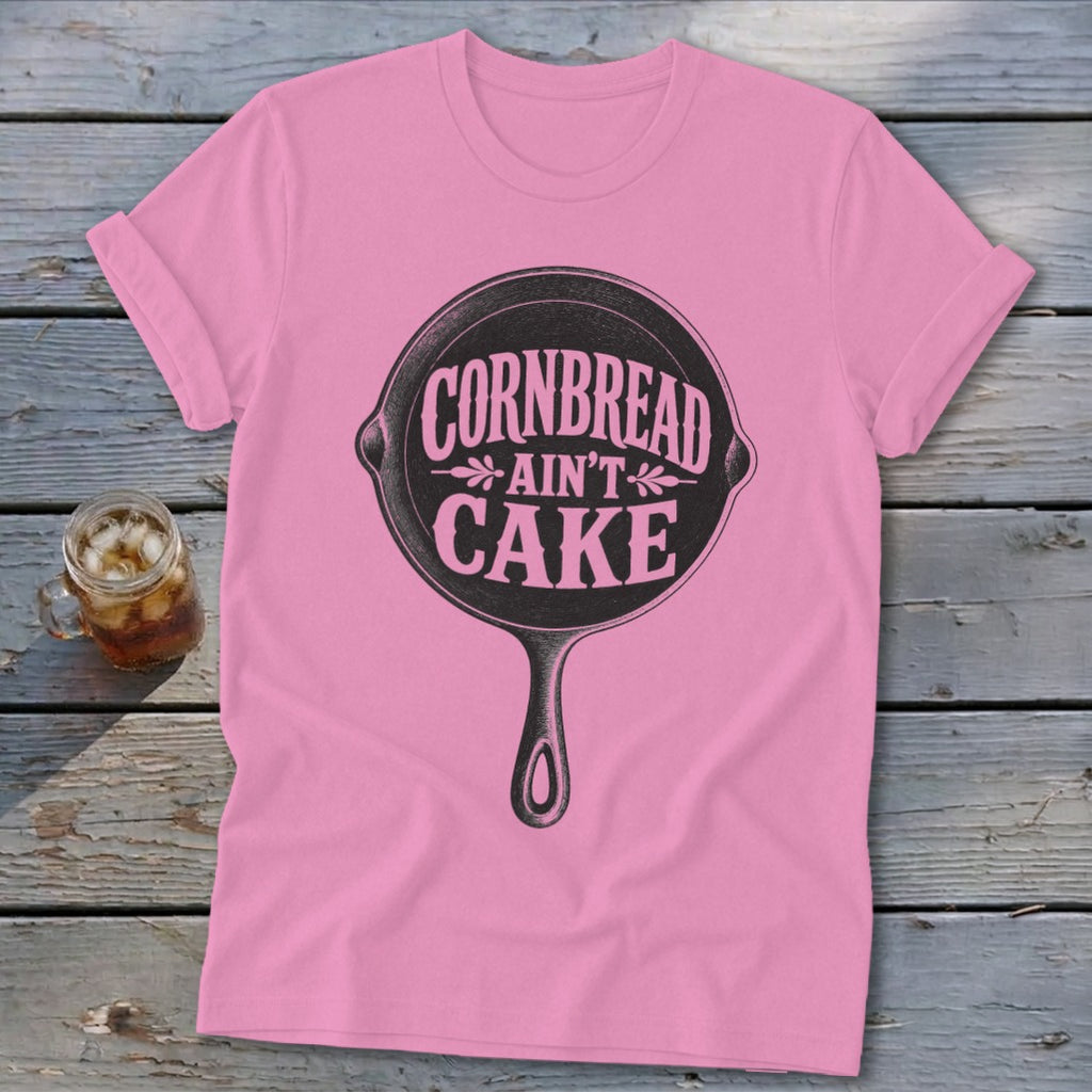 Pink t-shirt with black graphic of a cast iron skillet reading "Cornbread Ain't Cake".