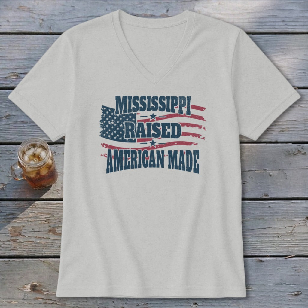 Light gray V-neck t-shirt featuring a distressed graphic of the American flag and the text Mississippi Raised American Made.