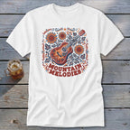 A white t-shirt featuring a folk-art graphic of a guitar, sunflowers, and the text MOUNTAIN MELODIES.