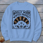 Light blue crewneck sweatshirt featuring a black graphic of a woolly worm and text reading Woolly Worm Winter Prophet.