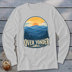 Light gray long-sleeve t-shirt with a vintage graphic of layered blue mountains, evergreen trees, and a setting sun labeled OVER YONDER.