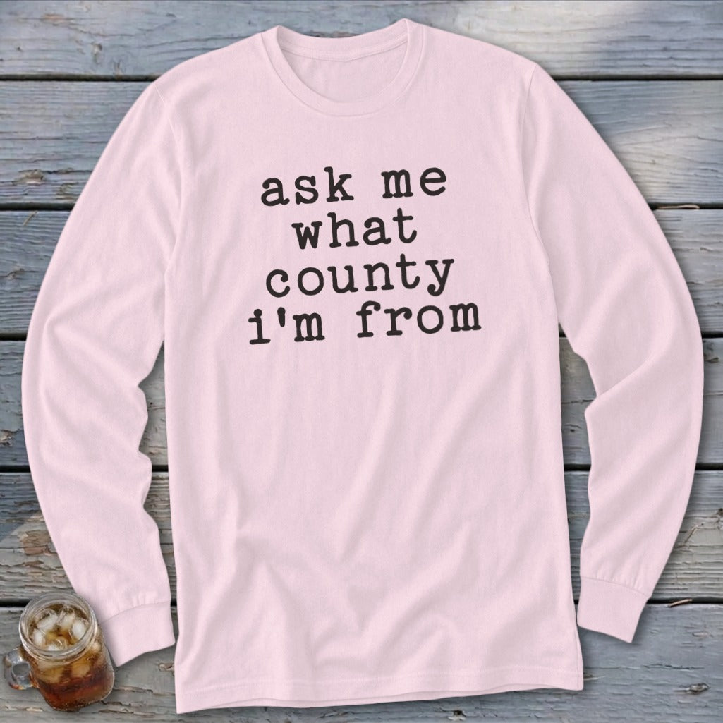 Light pink long sleeve shirt with black text asking "ask me what county I'm from."