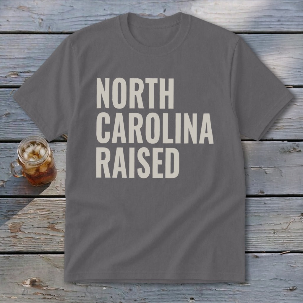 Gray t-shirt with "NORTH CAROLINA RAISED" text, glass of iced tea nearby.