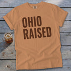 Orange t-shirt with brown "OHIO RAISED" text and a glass of iced tea.