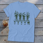 Light blue t-shirt featuring a green graphic of four mason jars filled with wildflowers on a shelf.