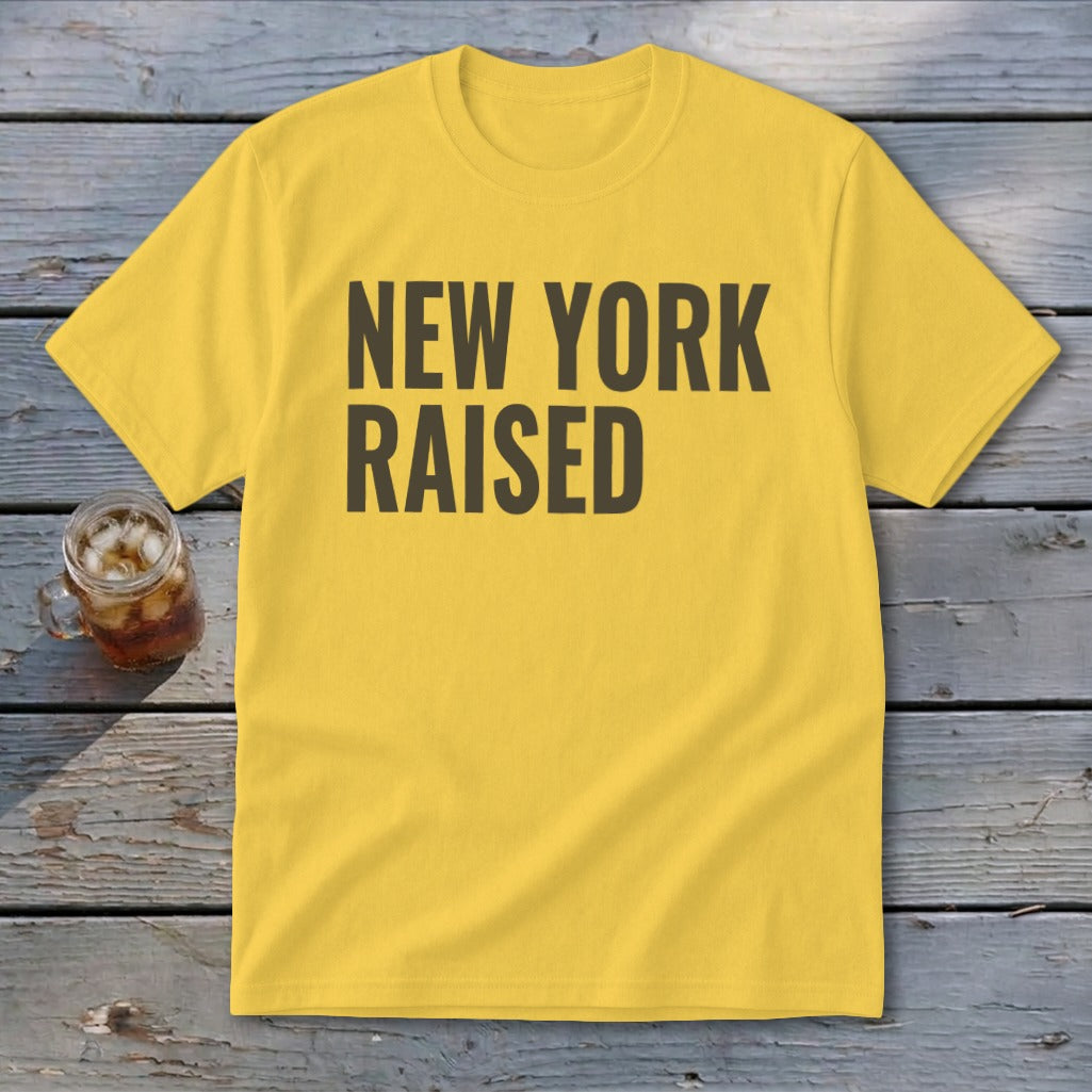 Yellow t-shirt with "NEW YORK RAISED" text, next to a glass of iced tea.
