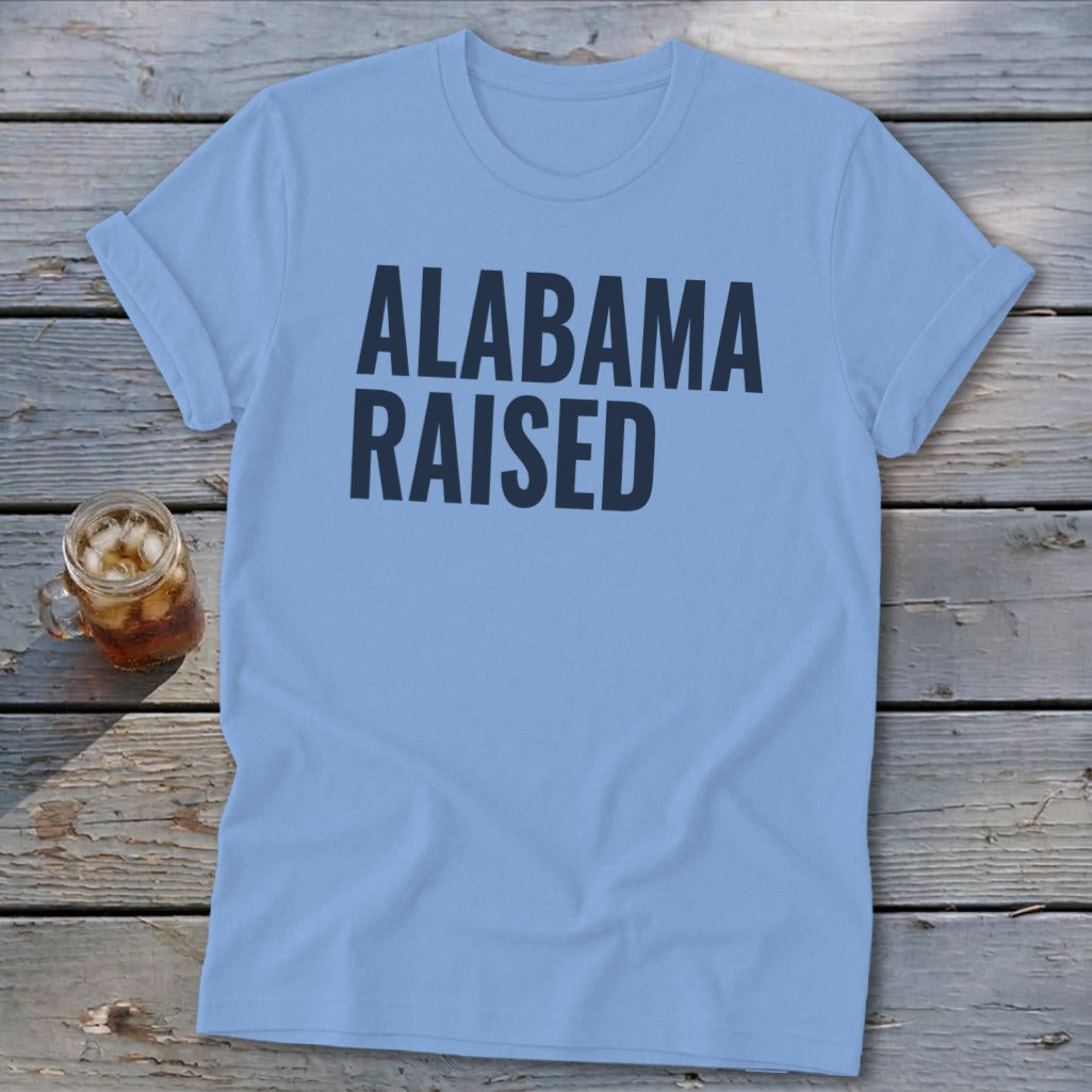 Light blue t-shirt with "ALABAMA RAISED" in dark blue text.