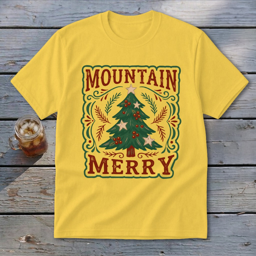 A yellow t-shirt features a vintage-style Christmas tree graphic with the text Mountain Merry on a wooden surface.