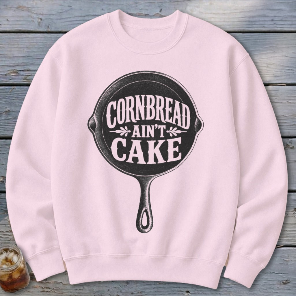 Pink sweatshirt with black graphic of cast iron pan and text "Cornbread Ain't Cake."