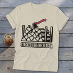 Cream t-shirt with graphic of axe over stacked firewood and text "STACKED FOR THE SEASON".