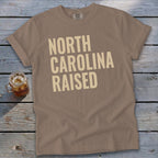T-shirt with "NORTH CAROLINA RAISED" text in large, light-colored font.
