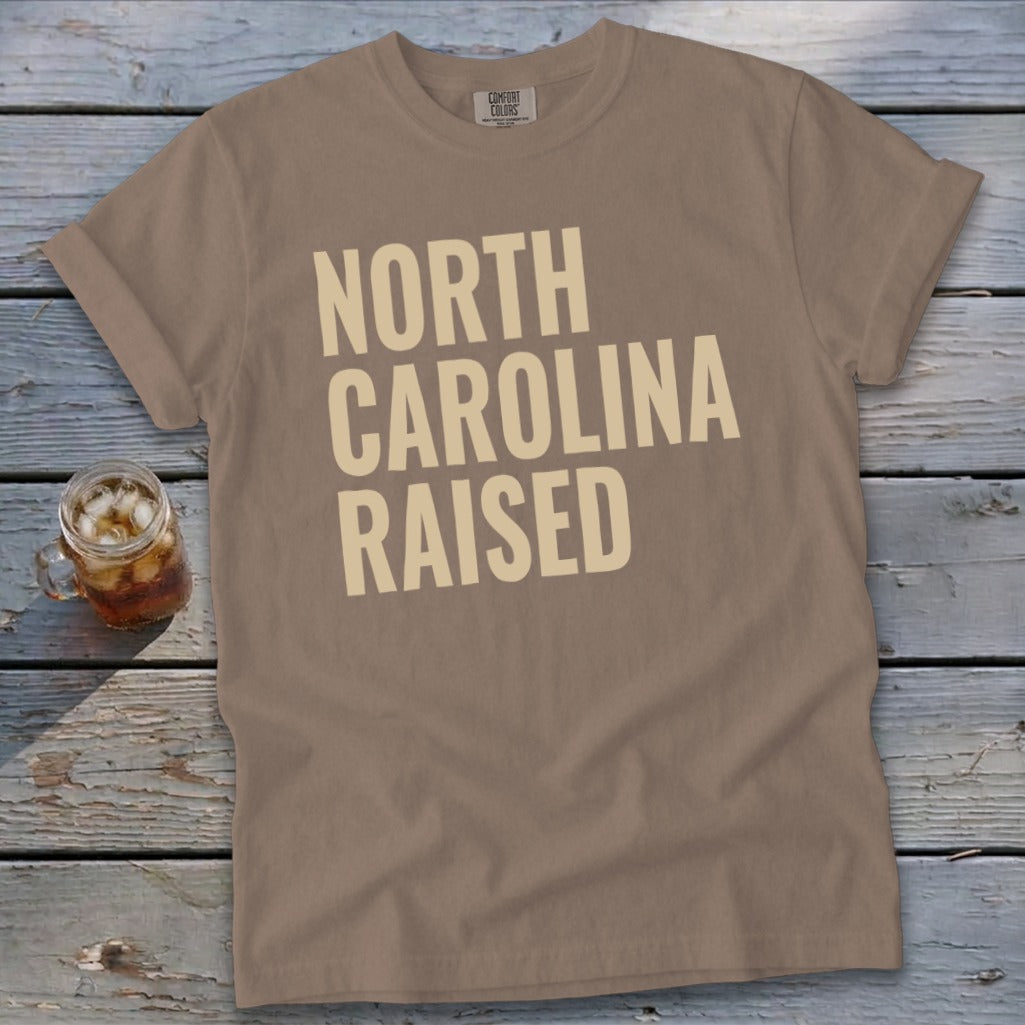 T-shirt with "NORTH CAROLINA RAISED" text in large, light-colored font.