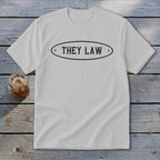 White t-shirt with "THEY LAW" text in an oval emblem.