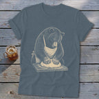 Bear wearing apron kneading dough on a wooden cutting board.