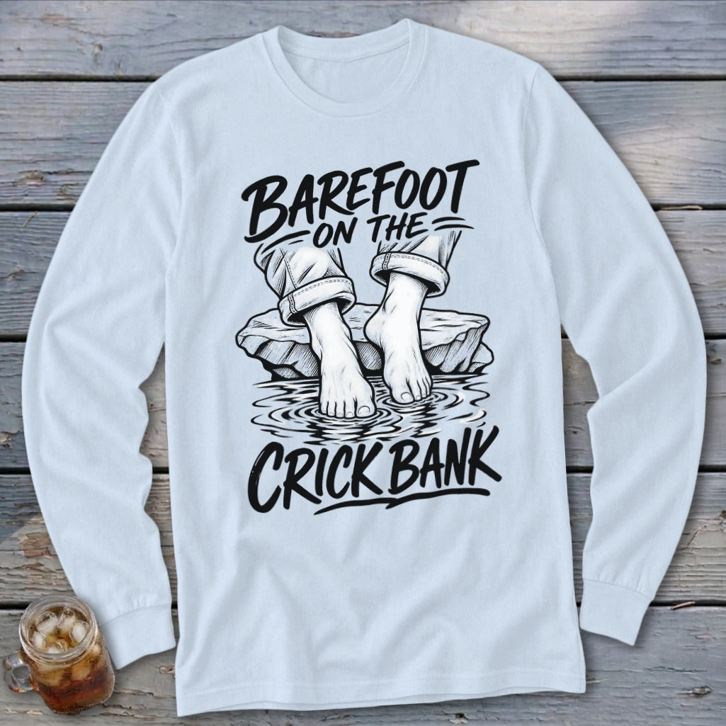 Light blue long-sleeve shirt with black graphic text and illustration of bare feet by water.