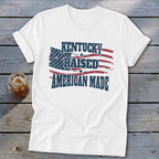 White t-shirt with distressed American flag graphic and text "KENTUCKY RAISED AMERICAN MADE".