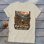 T-shirt with rocking chairs, pumpkins, and autumn mountains, reads "Pull up a chair."