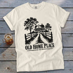 T-shirt with black graphic of a farmhouse, trees, fence, and text "OLD HOME PLACE".