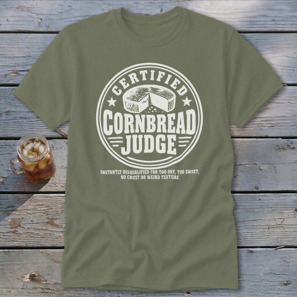 An olive green t-shirt with a white graphic reading Certified Cornbread Judge and a cornbread wheel.