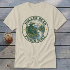 Cream t-shirt with "Holler Bear Fishin Hole" graphic of bear fishing by a river.