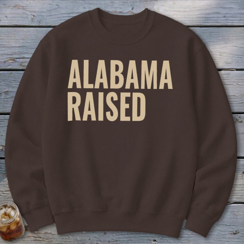 Brown sweatshirt with "ALABAMA RAISED" text in tan letters.