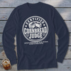 Navy blue long-sleeved t-shirt featuring a white round graphic with a cornbread illustration and text reading Certified Cornbread Judge.